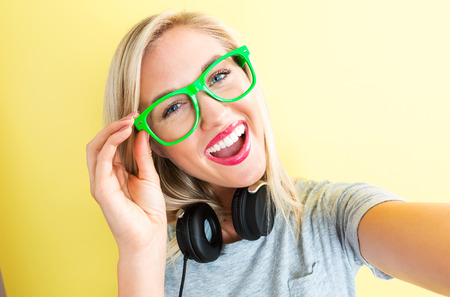 Happy young woman with headphones on a yellow background