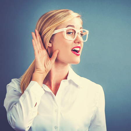 Young woman listening on a gray backgroundの写真素材