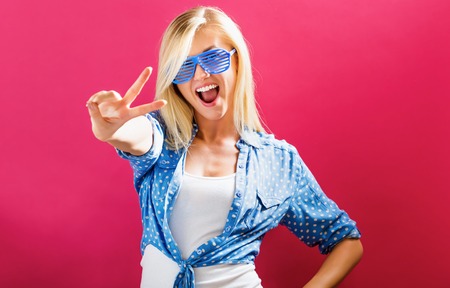 Young woman wearing shutter shades sunglasses on a pink background