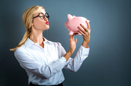 Young woman with a piggy bank on a gray backgroundの写真素材