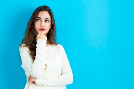 Young woman in a thoughtful pose on a blue backgroundの写真素材
