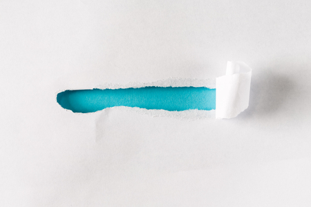 Torn slit of piece of paper revealing blue backgroundの写真素材