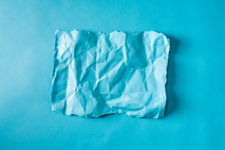 Blank piece of crumpled paper on a blue backgroundの写真素材