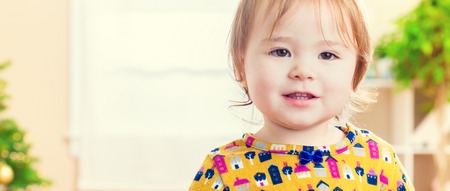 Happy toddler girl standing in her bright roomの写真素材