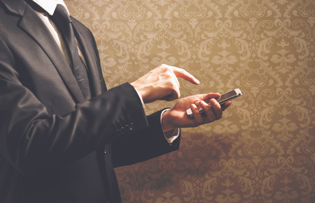 Businessman using a smartphone on a dark backgroundの写真素材