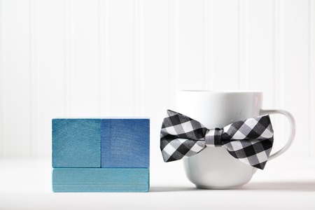 White mug with bowtie and blue wooden blocksの写真素材