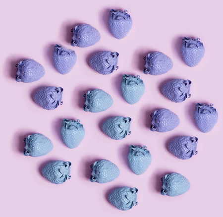 Purple and blue painted strawberries on a pink backgroundの写真素材