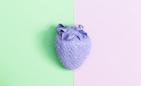 Purple painted strawberry on a pastel pink and green backgroundの写真素材