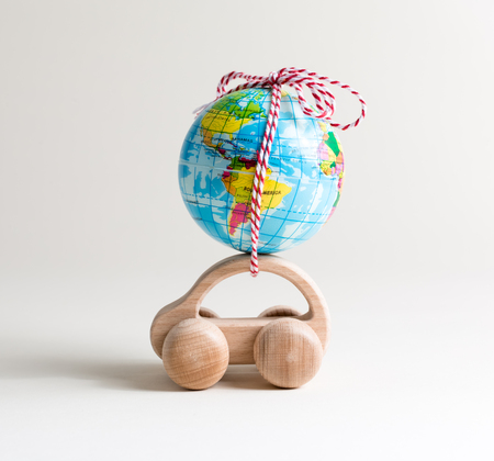 Miniature toy car carrying a small globeの写真素材