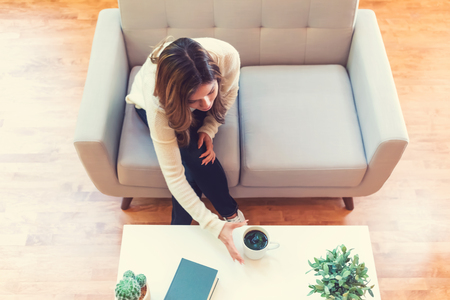 Young hispanic woman drinking coffee at homeの写真素材