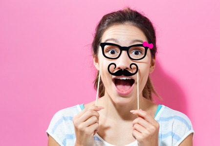 Young woman holding paper party sticks on a solid color backgroundの写真素材