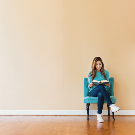 Young latina woman reading a book in a large interior roomの写真素材