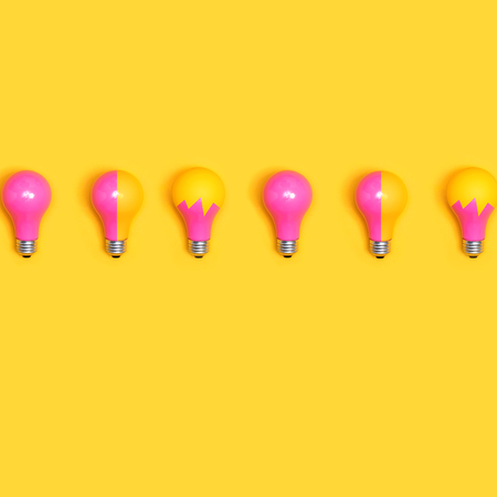 Colored light bulbs aligned on a yellow background