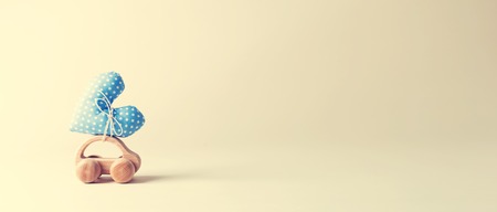 Toy car carrying a heart on an off white backgroundの写真素材