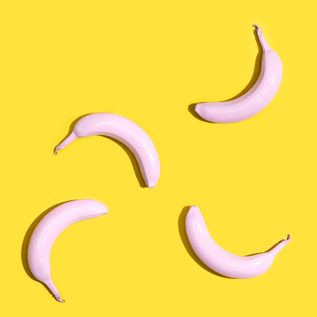 Series of painted pink bananas on a yellow backgroundの写真素材
