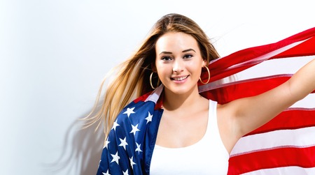Happy young woman holding American flag on a white backgroundの写真素材