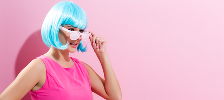 Portrait of a woman in a bright blue wig on a pink backgroundの写真素材