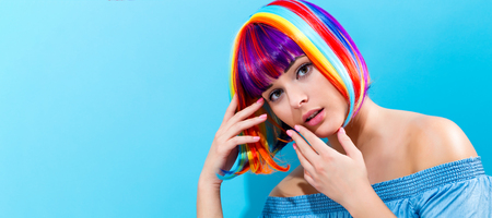 Beautiful woman in a colorful wig on a blue backgroundの写真素材