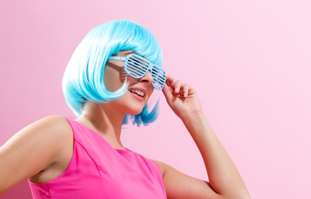 Portrait of a woman in a bright blue wig on a pink backgroundの写真素材