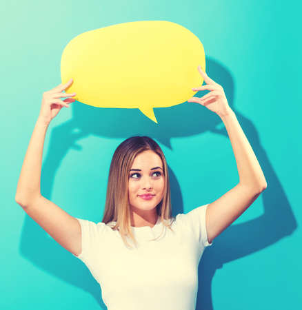 Young woman holding a speech bubble on a blue background