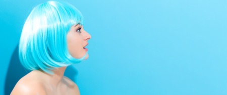 Beautiful woman in a bright blue wig on a blue backgroundの写真素材