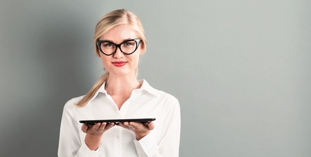 Young woman using her table on a gray backgroundの写真素材