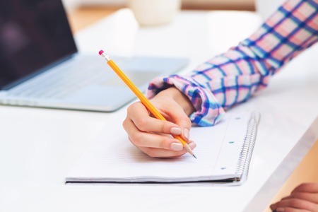 Woman writing in a notebook in a bright officeの写真素材