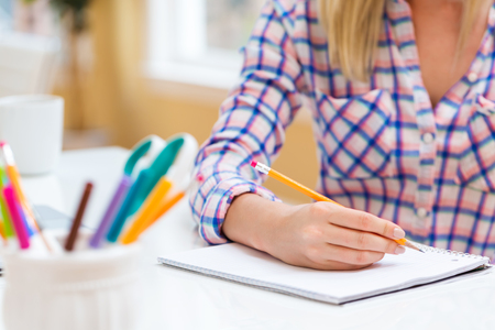 Woman writing in a notebook in a bright officeの写真素材