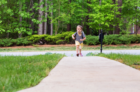 Happy Toddler girl arriving home from school with a backpackの写真素材