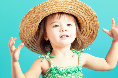 Happy toddler girl with a big straw hat in the summerの写真素材