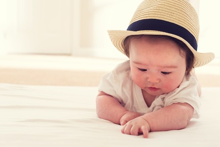 Happy baby boy with a straw hatの写真素材