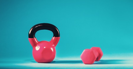 Pink kettlebell and dumbbell on a blue gradient backgroundの写真素材
