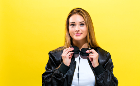Happy young woman with headphones on a yellow backgroundの写真素材