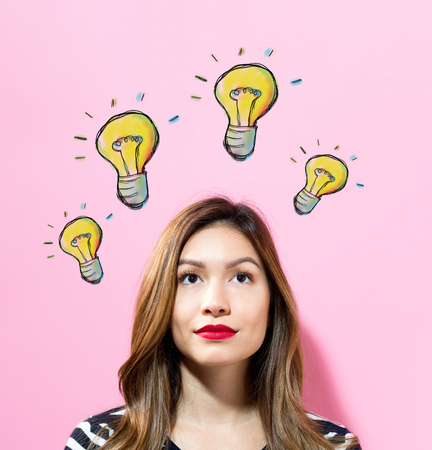 Light Bulbs with young woman on a pink backgroundの写真素材