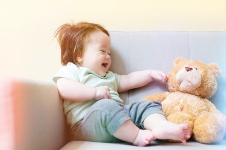 Happy baby boy playing with his teddy bear