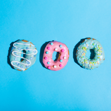 Colorful glazed donuts on a bright blue backgroundの写真素材