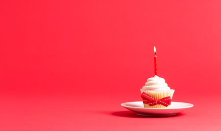 Cupcake with candle celebration theme on a red backgroundの写真素材