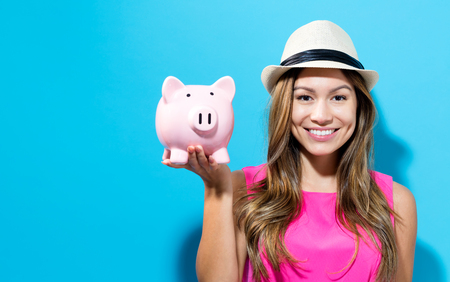 Young woman with a piggy bank on a blue backgroundの写真素材
