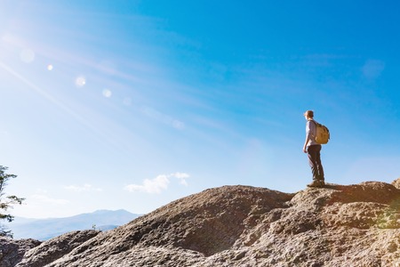 Man walking on the edge of a cliff high above the mountainsの写真素材