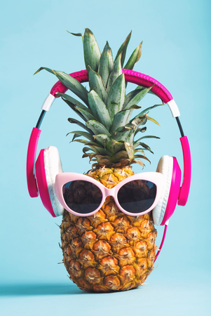 Pineapple with headphones and glasses on a bright backgroundの写真素材