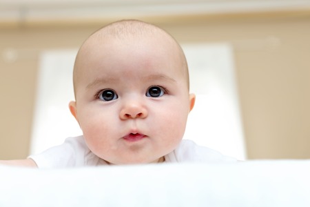 Happy newborn baby girl smiling at home