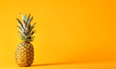 Whole pineapple on a bright yellow backgroundの写真素材