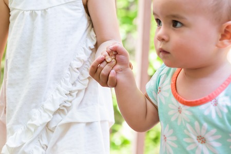 Toddler sisters holding hands outside in summerの写真素材