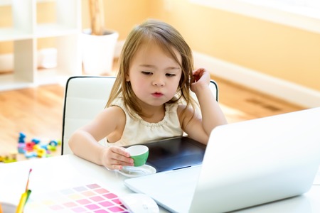 Little girl at her desk and computer at homeの写真素材