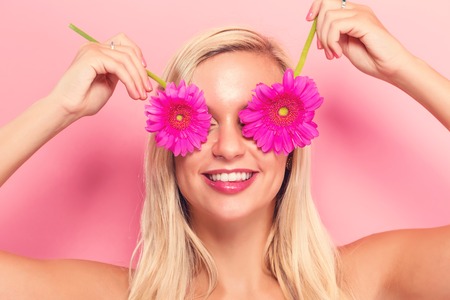 Young woman with pink garberas on a pink backgroundの写真素材