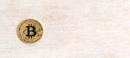 Gold bitcoin cryptocurrency on a wooden tableの写真素材