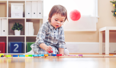 Happy toddler girl playing with toys in her houseの写真素材