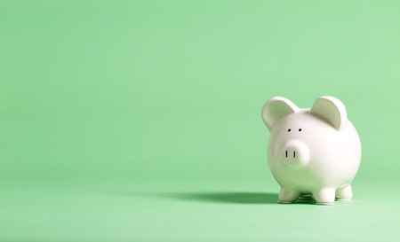 White piggy bank with glasses on a muted green backgroundの写真素材