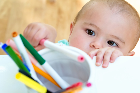 Toddler girl reaching for a jar of markersの写真素材