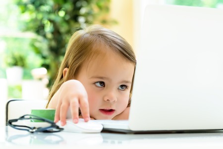 Little girl at her desk and computer at homeの写真素材